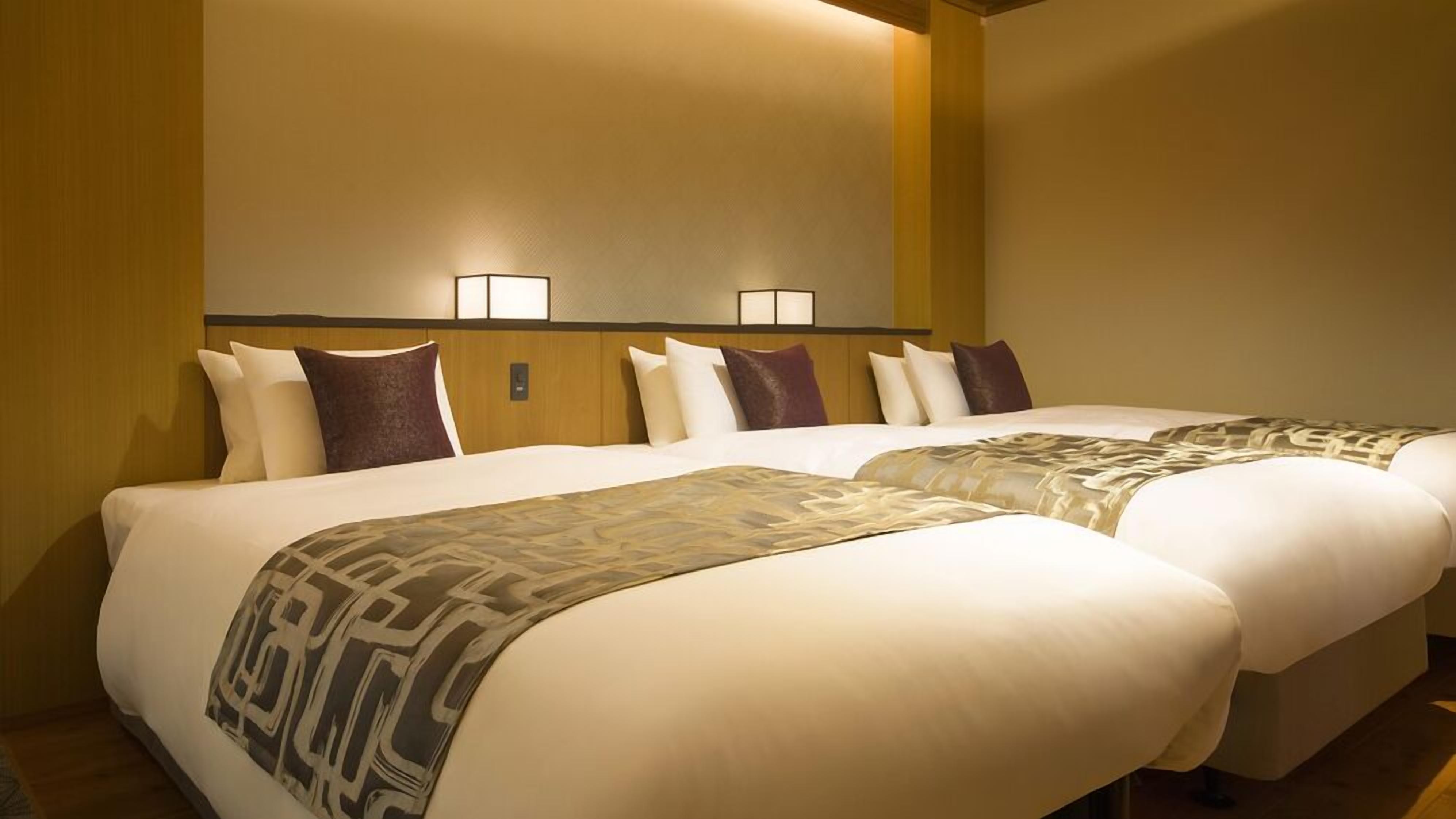 A hotel room with two beds, a wooden headboard, and two wall-mounted lamps.