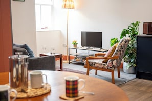 Een woonkamer met een bank, fauteuil, salontafel en televisie.
