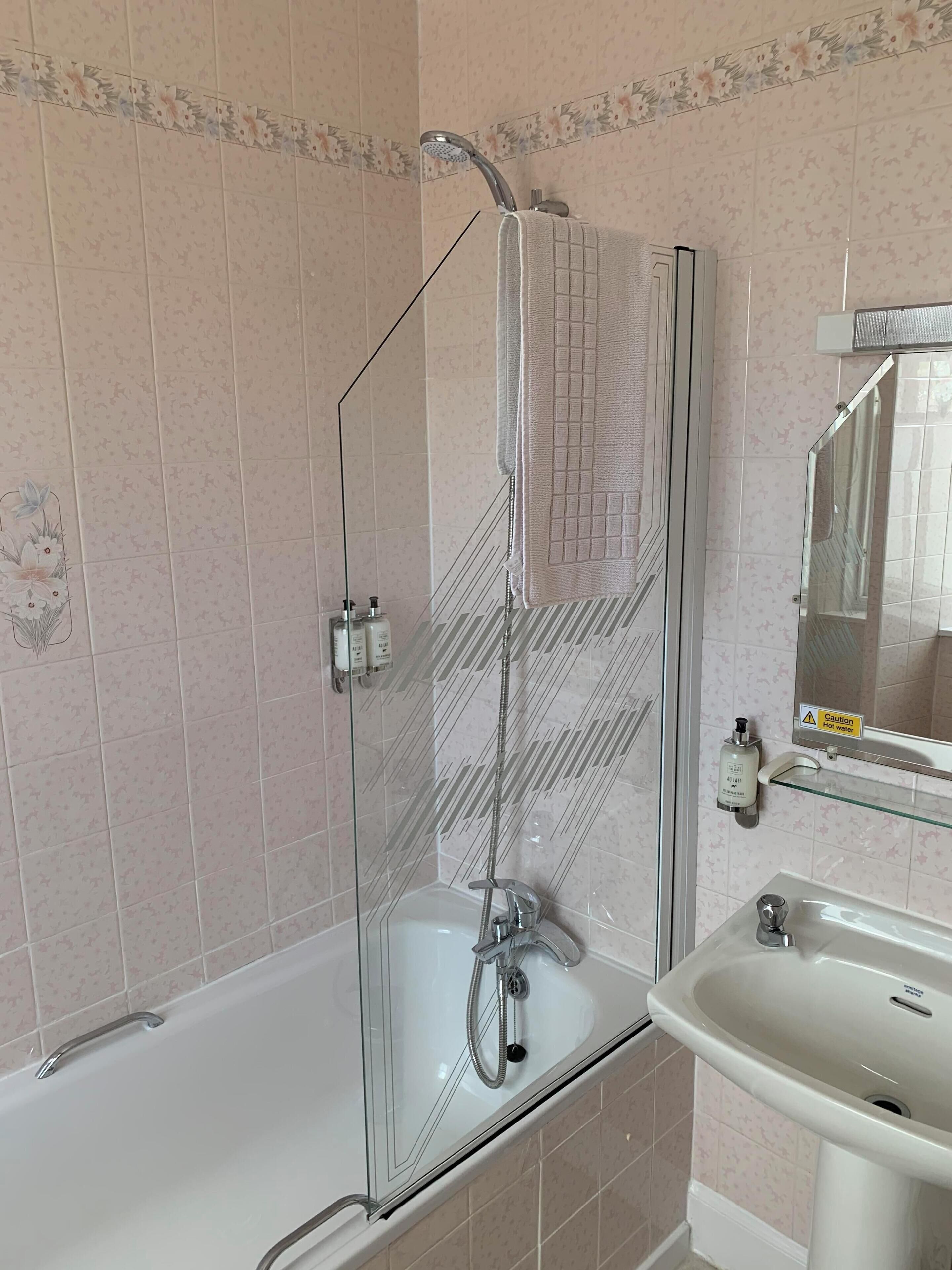 A bathroom with a glass-enclosed shower, a white bathtub, and a sink with a mirror.
