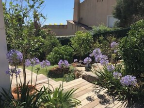 Stroll through the beautifully maintained garden, featuring a variety of plants and flowers, along a meandering pathway.