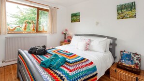 Une chambre à coucher avec un lit, une fenêtre, un radiateur et un tableau accroché au mur.