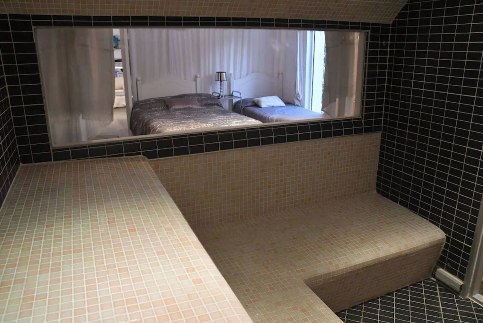 A bathroom with a small window, a bed, and a bathtub.
