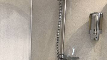 A shower with a handheld showerhead, a wall-mounted shampoo dispenser, and a towel rack.