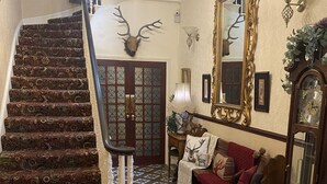 A grand staircase with ornate railings, a patterned carpet, and a large mirror with a deer head. - Cornerways Guest House (Carlisle)