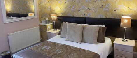 A neatly made bed with a floral bedspread, a headboard, and two bedside lamps.