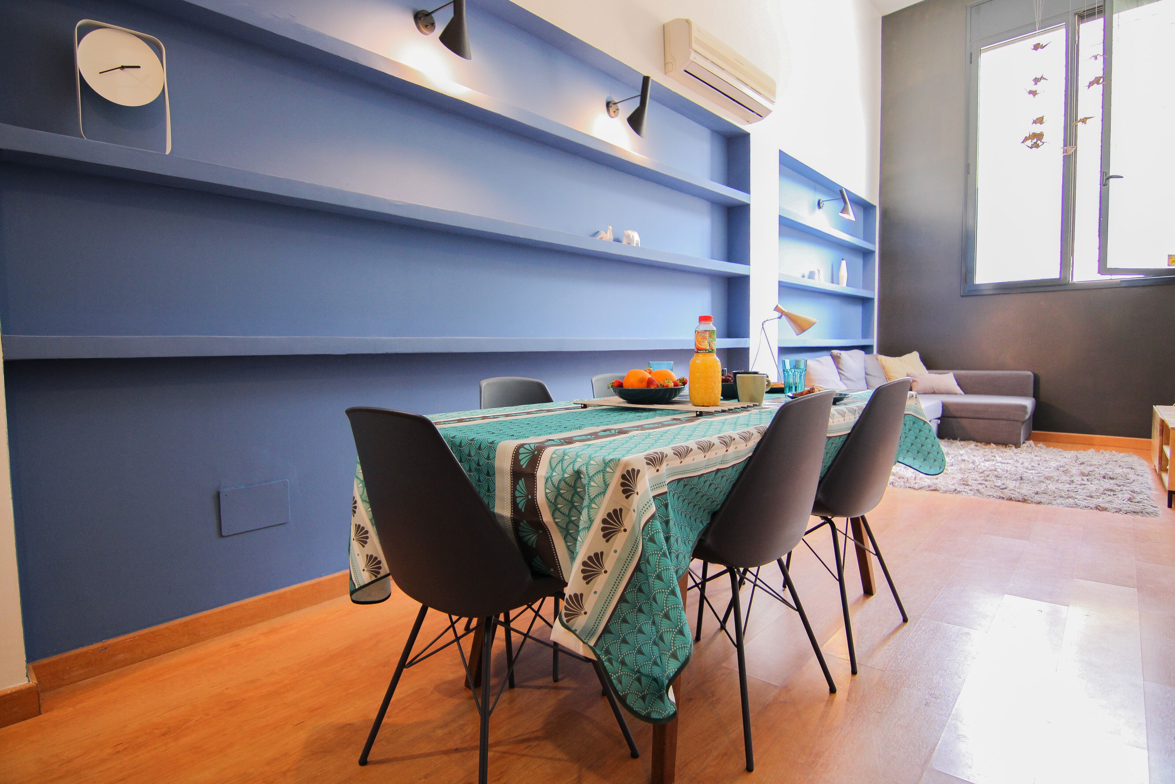 A dining area with a table set for four, chairs, a fruit bowl, and a bottle of orange juice.