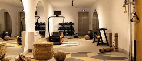 A gym with exercise equipment, a mirror, and a patterned floor.