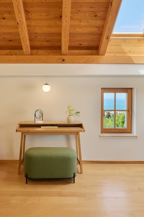 A room with a wooden ceiling, a skylight, a wooden desk, a green bench, a small table with a plant, and a window with a view. - Palace Natali (Dubrovnik)