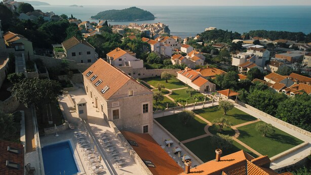 A coastal town with stone buildings, a swimming pool, and a view of the sea. - Palace Natali (Dubrovnik)