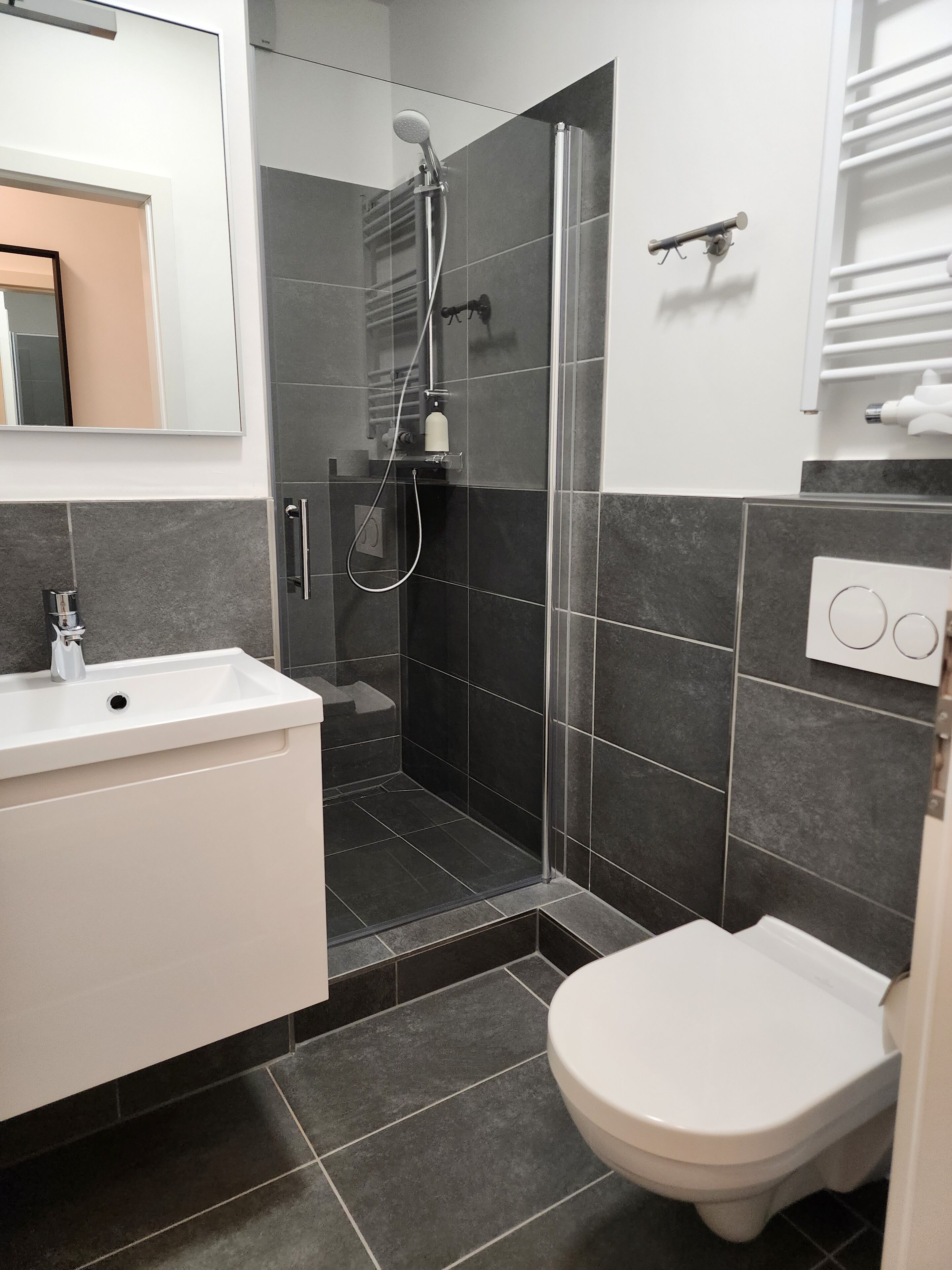 Uma casa de banho moderna com chuveiro, sanita e lavatório.