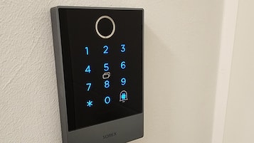 A wall-mounted electronic keypad with a numeric keypad and a circular button at the top.
