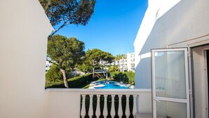 Ein Balkon mit Blick auf einen Pool, umgeben von Grünflächen und Gebäuden.