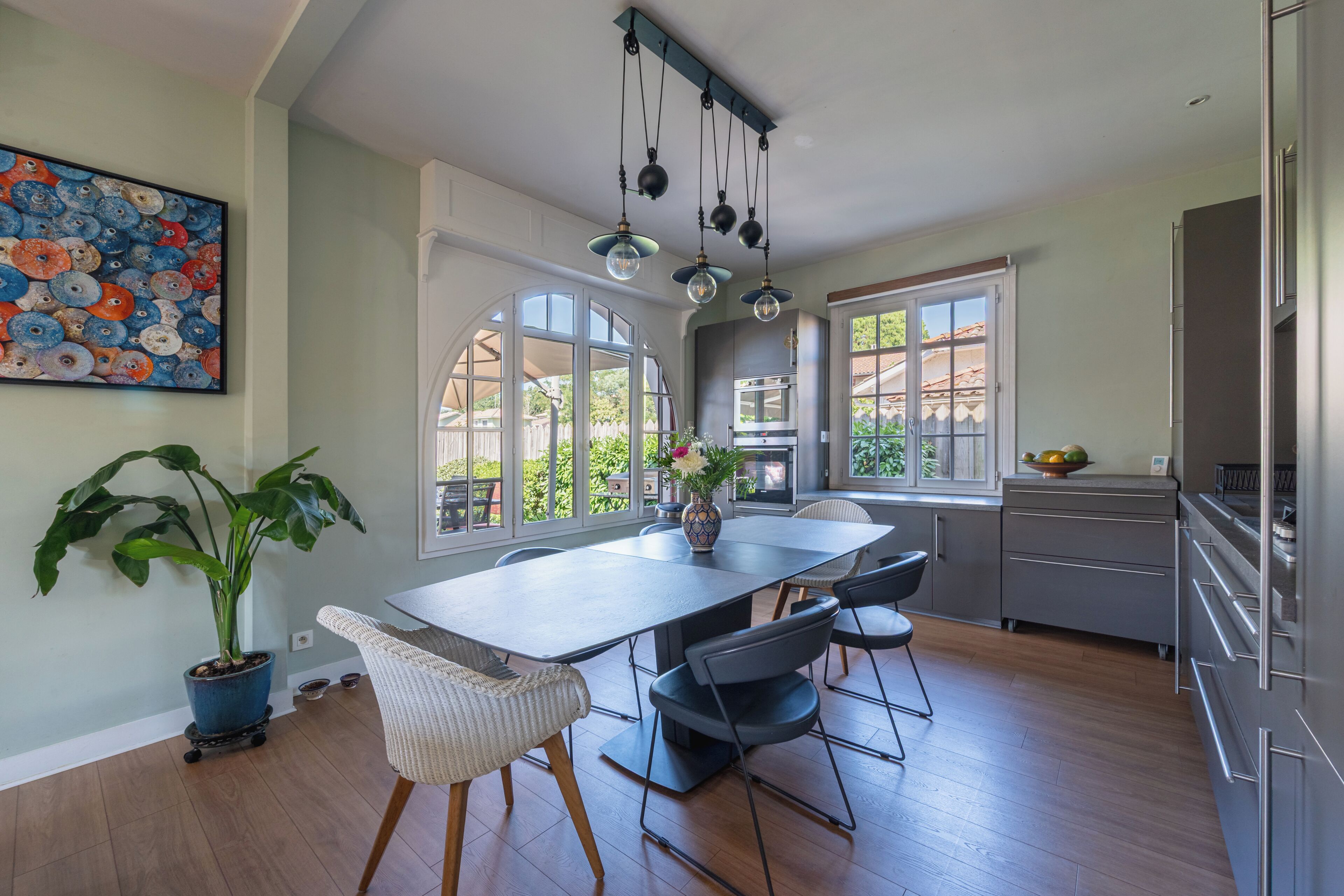 A modern kitchen with a large island, pendant lighting, and a view of the outdoors.