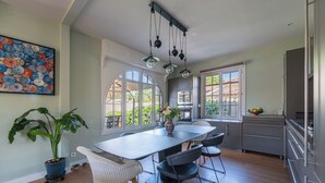 Een moderne keuken met een groot kookeiland, hangende lampen en uitzicht op de omgeving.