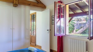 Een slaapkamer met een bed, een raam en een deur naar buiten.