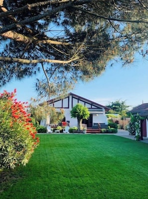 A modern house with a well-maintained lawn, a patio with outdoor furniture, and a small garden area.