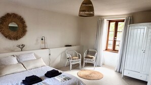 A bedroom with a large bed, two white chairs, a wardrobe, and a window with curtains. - Gîte Tranquille Avec Piscine Partagée (Crespin)