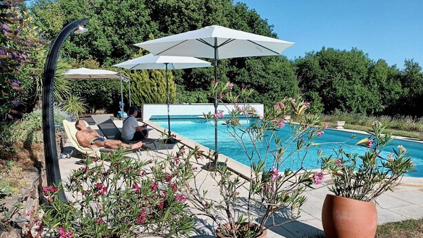 A poolside area with a swimming pool, lounge chairs, and potted plants. - Gîte Tranquille Avec Piscine Partagée (Crespin)