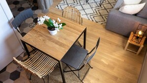 A dining area with a wooden table, woven chairs, and a potted plant. - Rooftop Mirabeau • Private Roof Terrace • A/C • 2 Bedrooms (Aix-en-Provence)