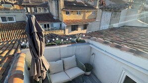 A rooftop terrace with a sofa set, a small table, and an umbrella. - Rooftop Mirabeau • Private Roof Terrace • A/C • 2 Bedrooms (Aix-en-Provence)