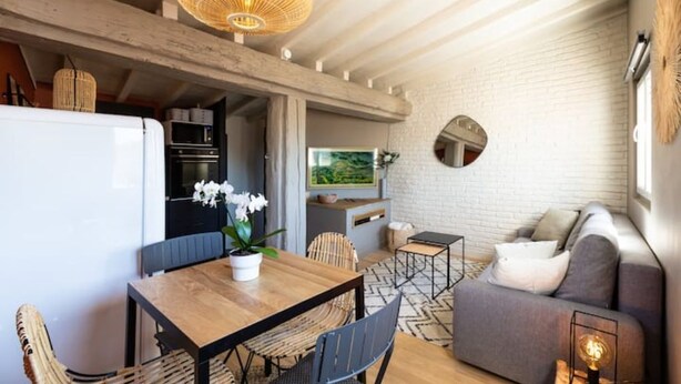 A modern kitchen with white appliances, a dining area with a wooden table and chairs, and a living area with a sofa and a TV. - Rooftop Mirabeau • Private Roof Terrace • A/C • 2 Bedrooms (Aix-en-Provence)