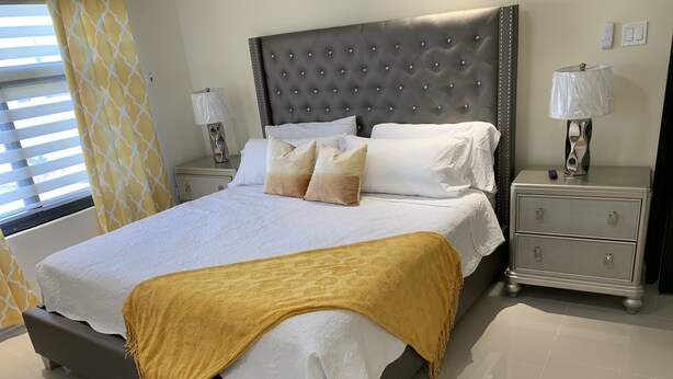 Una habitación de hotel moderna con una cama grande, dos mesitas de noche y una mesilla.