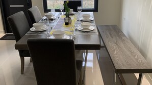 Un comedor con una mesa dispuesta para cuatro, un banco y vistas al exterior.