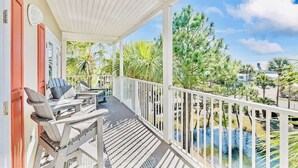 A covered outdoor area with white railings, two lounge chairs, and a small table. - Gulf Place Oceanview Condo — Sleeps 10, Heated Pool & Steps to Beach (Santa Rosa Beach)