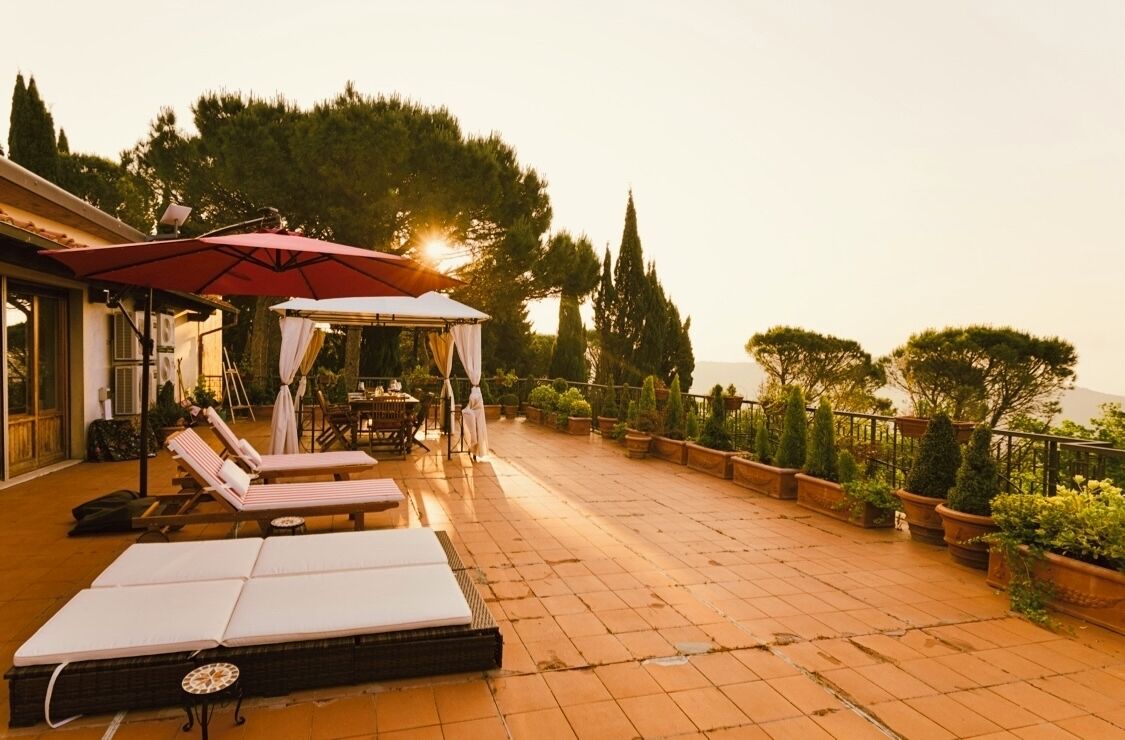 Una terraza en la azotea con sillones de descanso, una zona de estar cubierta y plantas en macetas.