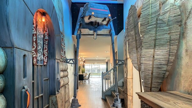 A modern interior with a stone wall, a wooden bench, and a ceiling with a hanging light fixture. - Star Wars 8BR | Arcade Game Rm | 2 Theaters | Pool (Kissimmee)