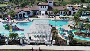 A large swimming pool with a slide, surrounded by lounge chairs and umbrellas. - Star Wars 8BR | Arcade Game Rm | 2 Theaters | Pool (Kissimmee)