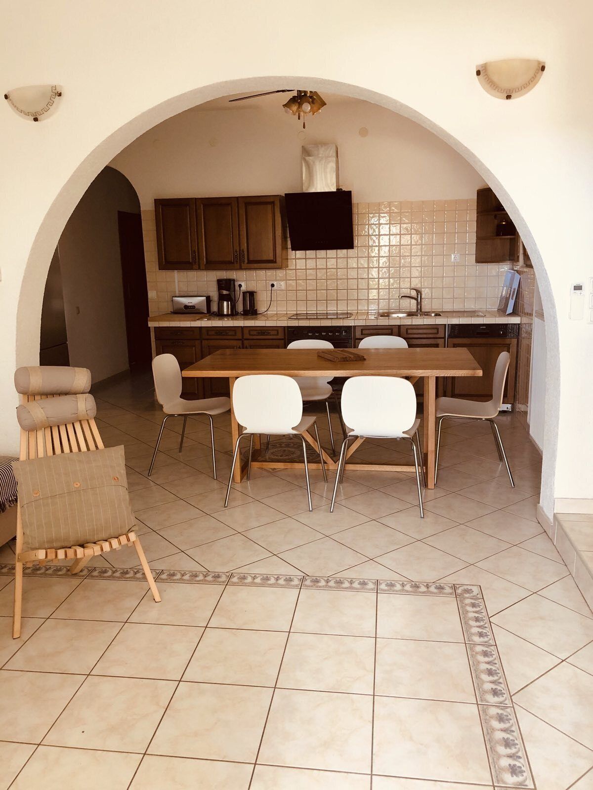 A kitchen with an archway, a dining table with chairs, and a sofa.