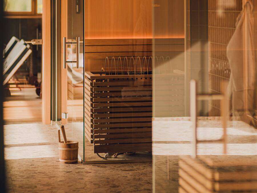 Un interior moderno con un separador de vidrio, muebles de madera e iluminación colgante.