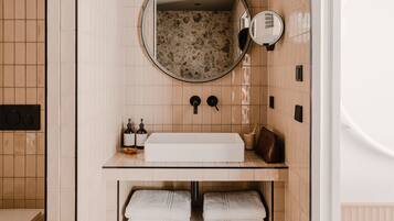 A bathroom with a freestanding sink, a round mirror, and a towel rack.