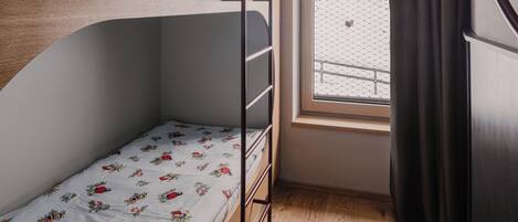 Dormitorio con literas, una ventana y una cortina.