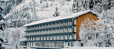 Un hotel de varios pisos con diseño moderno, situado en una zona montañosa nevada.