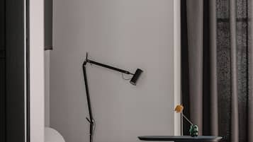 A modern living room with a grey sofa, a small side table, a black floor lamp, and a vase with a single flower.