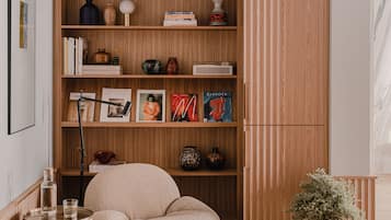 Una habitación acogedora con una estantería de madera, un sillón cómodo, una mesita auxiliar y un jarrón decorativo.