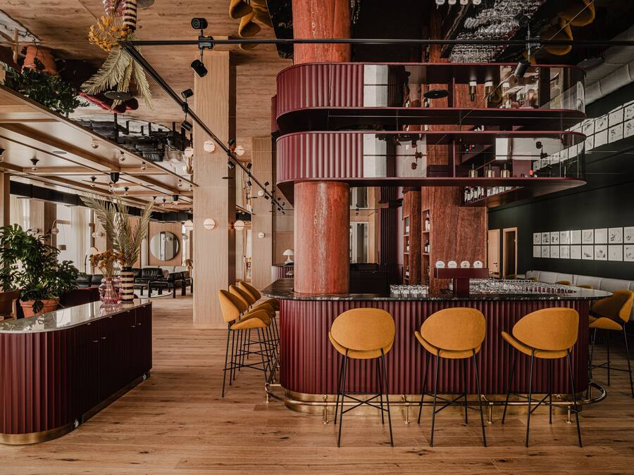 Zona de bar moderna con una columna central, taburetes de bar y suelo de madera.