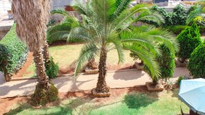 A garden with palm trees and a patio area. - leleshwa inn (Kitengela)