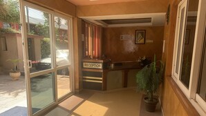 A reception area with a reception desk, a potted plant, and a sign indicating the reception. - leleshwa inn (Kitengela)