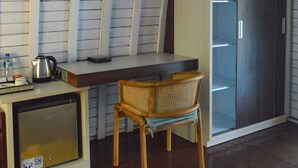 A room with a wooden ceiling, a television mounted on the wall, a desk with a chair, a wardrobe, and a small cabinet with a screen. - The MG Villa & SPA (Penida Island)