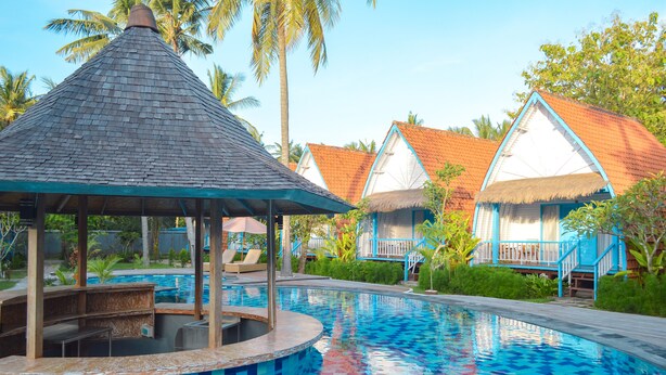 A swimming pool with a tiled edge, a gazebo, and thatched-roof huts with blue trim. - The MG Villa & SPA (Penida Island)