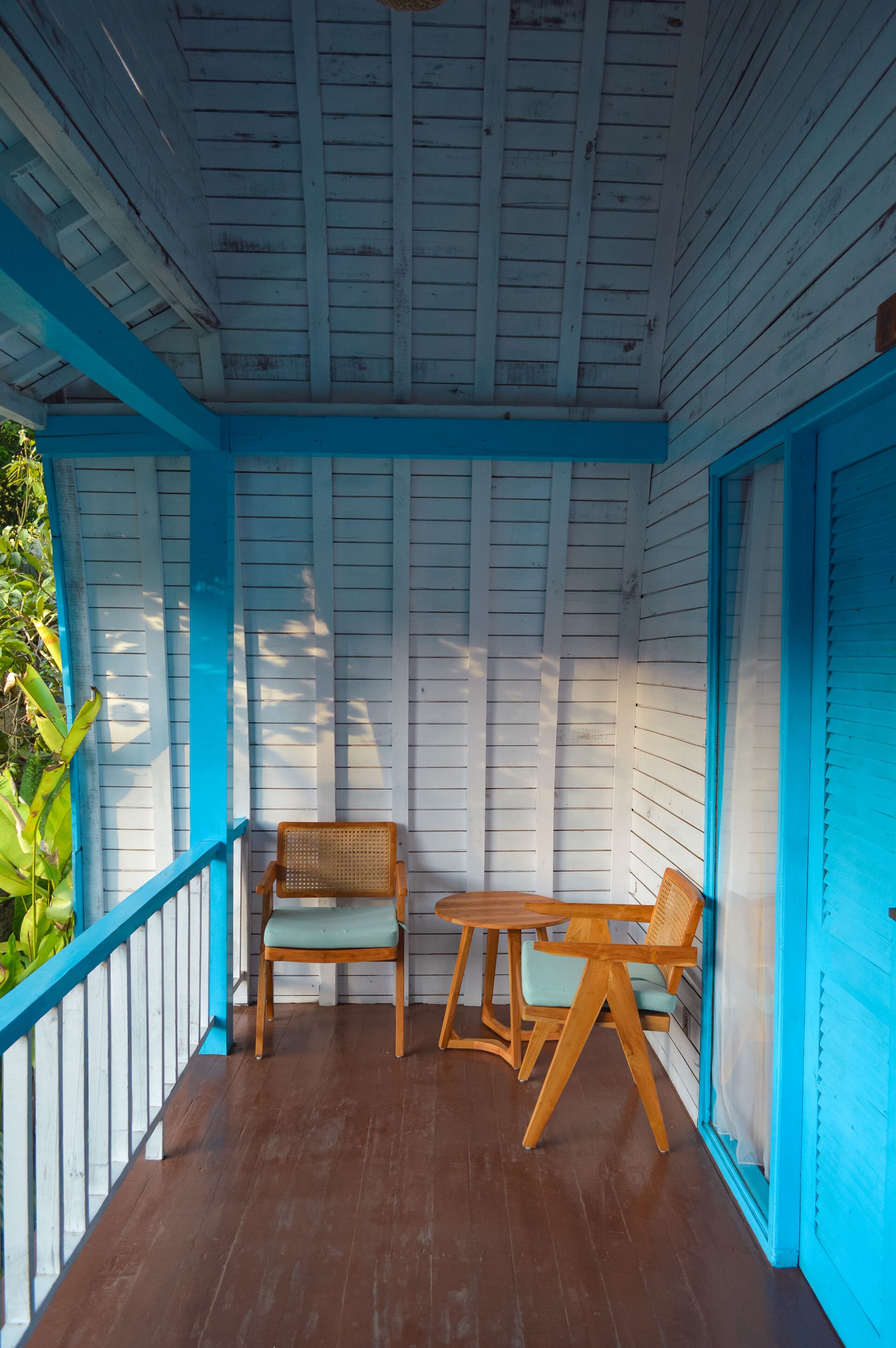 A covered porch with wooden furniture and a railing.