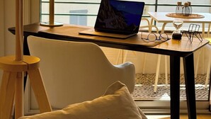 Een balkon met een laptop, een tafel en stoelen.