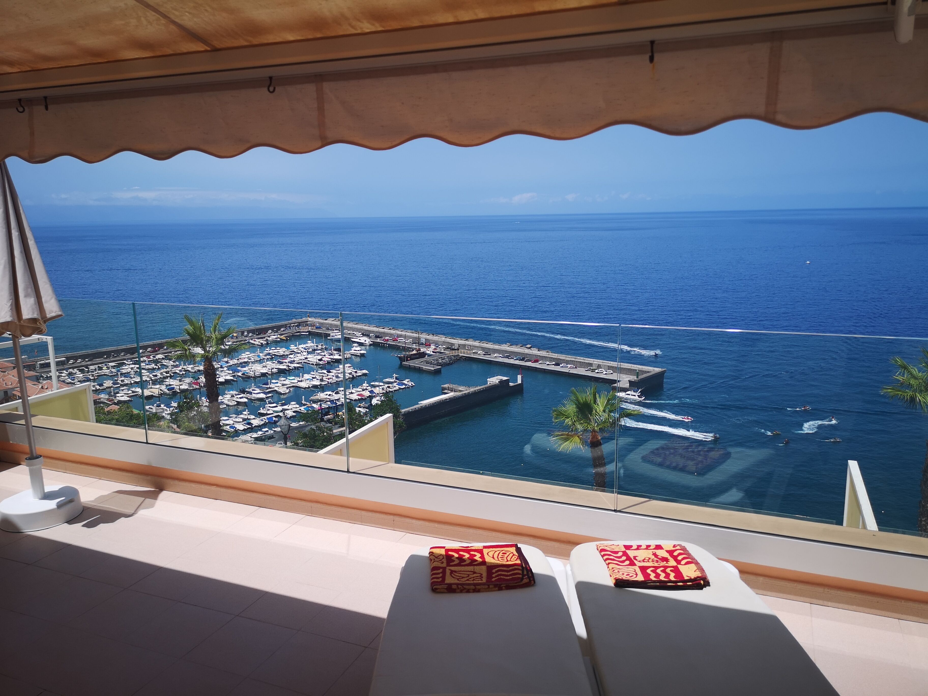 A balcony with a view of a marina and the ocean.