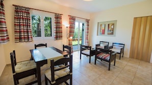 A dining area with a table and chairs, a bench, and curtains. - Theros Retreat (Kefalonia)