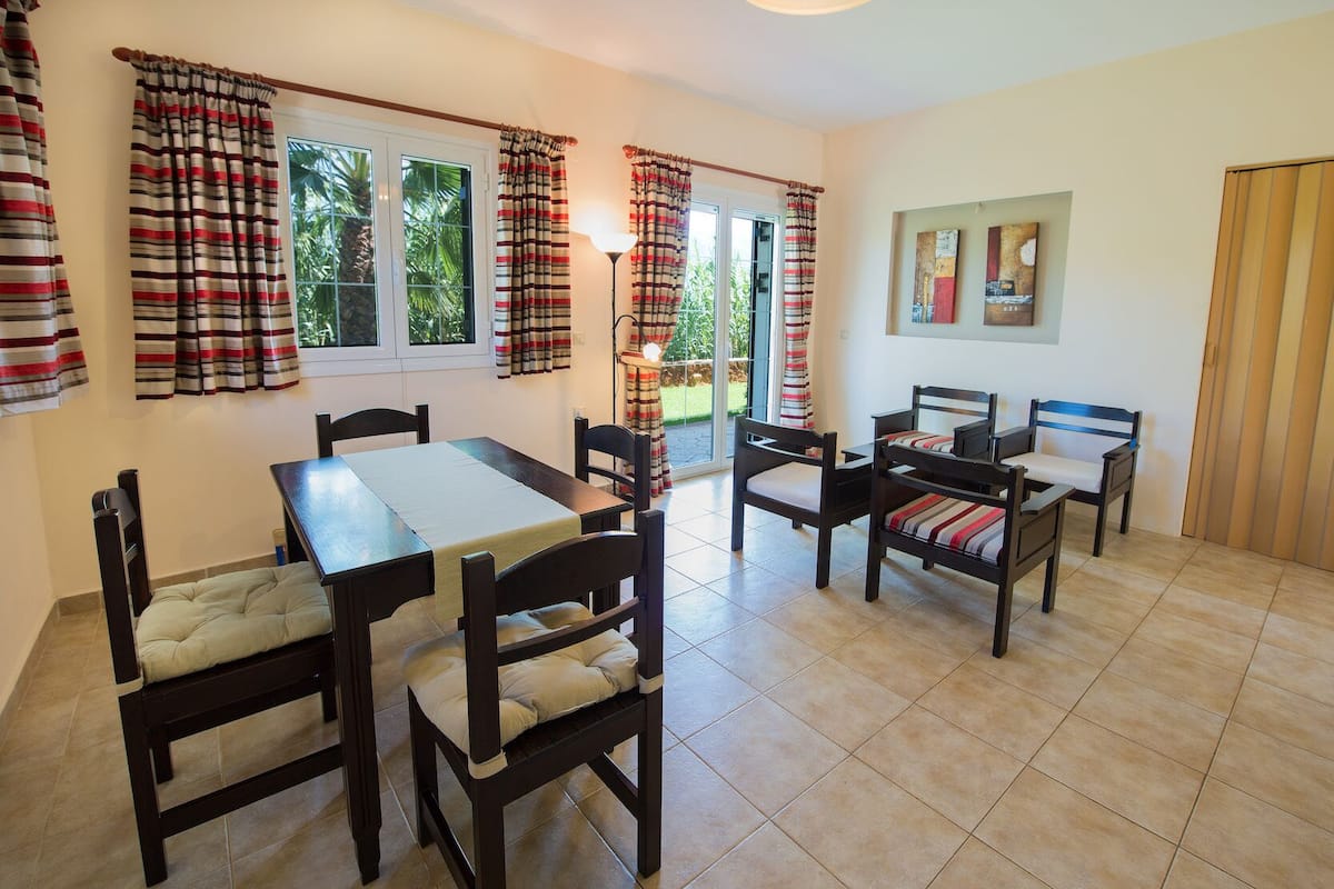 A dining area with a table and chairs, a bench, and curtains.