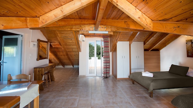 A spacious attic bedroom with a wooden ceiling, a bed, a desk, and a chair. - Theros Retreat (Kefalonia)