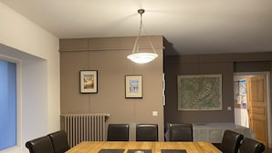 Una sala da pranzo con un tavolo di legno e sedie nere, quadri appesi alle pareti e una mappa.
